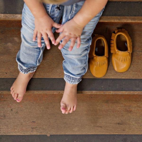 Boy sitting on stairs view from above barefoot soft sole shoes next to him