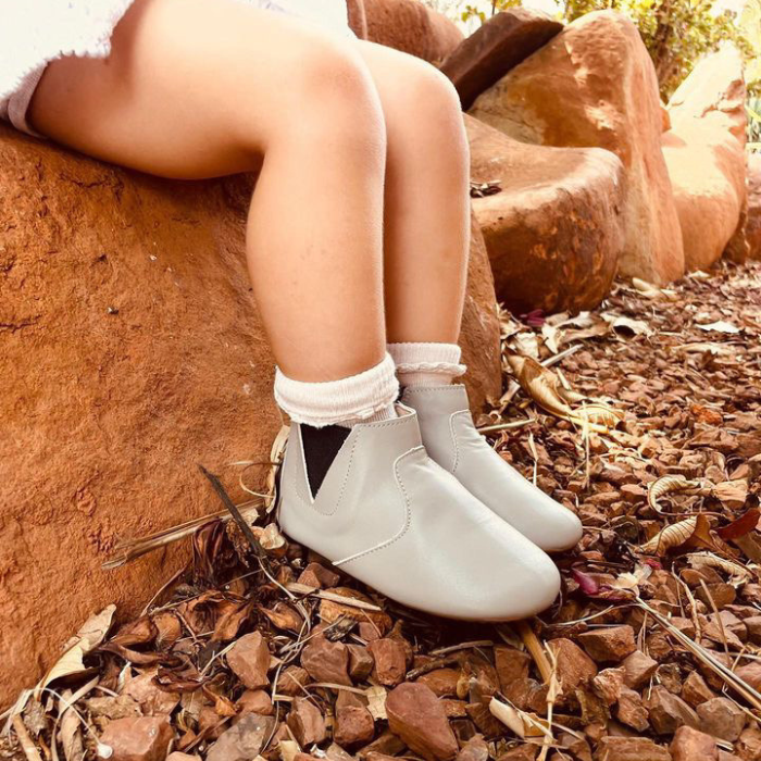Grey leather elastic side boots with zip ankle opening. Worn by a child sitting on a rock